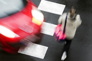 pedestrian crossing road in front of a fast moving car at crosswalk